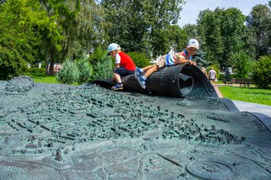 Russia, Yaroslavl - August 5, 2020: Small children play on a metal map of the city of Yaroslavl in Russia. Gulliver and the Lilliputians clipart