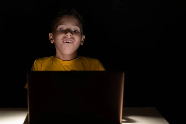 ラップトップの画面の前で暗闇の中に座っている非常に驚きの少年は 彼の目を大きく口を開けて — ストック写真