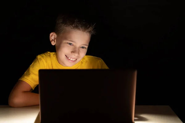 Menino Alegre Senta Quarto Escuro Olha Para Tela Laptop Sorrindo — Fotografia de Stock