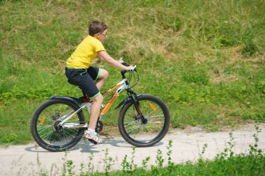 Çocuk parkta bisiklet sürüyor.