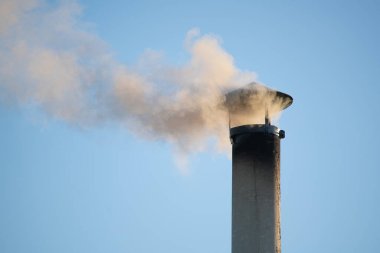 Binanın çatısındaki baca borusundan duman çıkıyor..