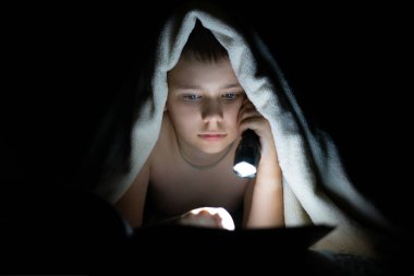 Çocuk karanlıkta ders alır, fenerle aydınlatır.