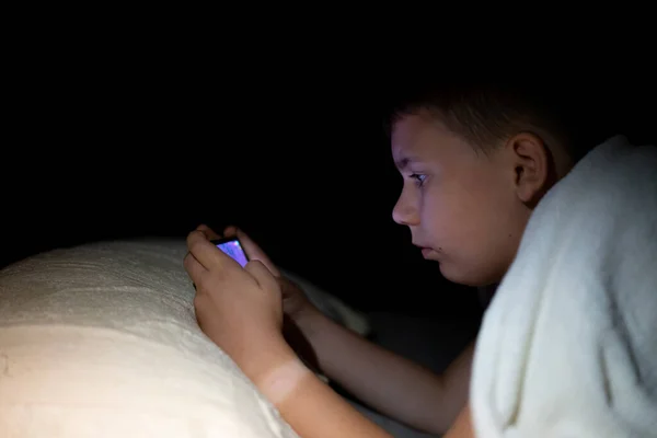 Menino Jogando Telefone Noite Escuro Deitado Cama — Fotografia de Stock