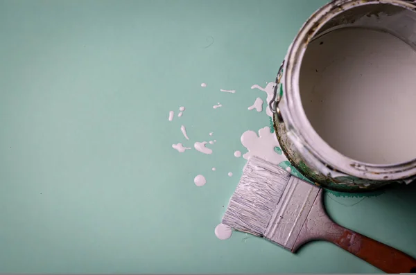 white paint pot with smeared bucket of white paint dripping on a light green background