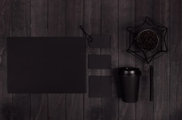 Coffee shop template for branding identity - black paper cup,   blank label, card, paper statuette with coffee beans on black wood board.