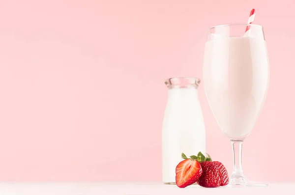 甜草莓奶昔在精致的酒杯与奶瓶 切片浆果 秸秆在浅色粉红色的背景 — 图库照片