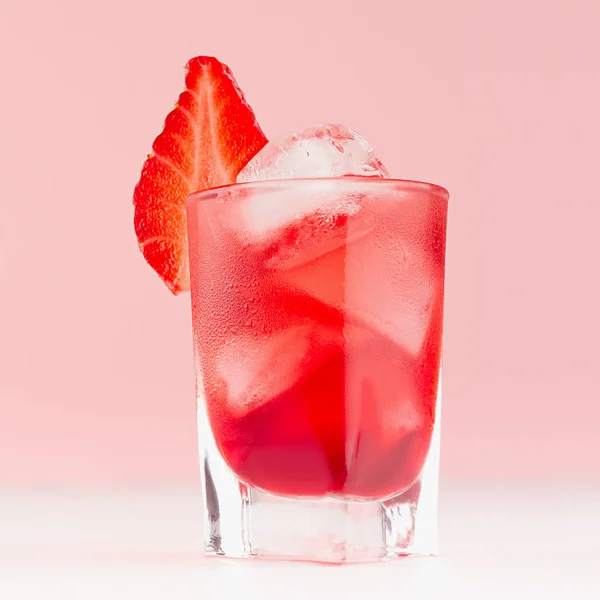 新鲜冷水果鸡尾酒在优雅的射击玻璃与冰块 草莓片在柔和的粉红色背景和白色木桌 — 图库照片