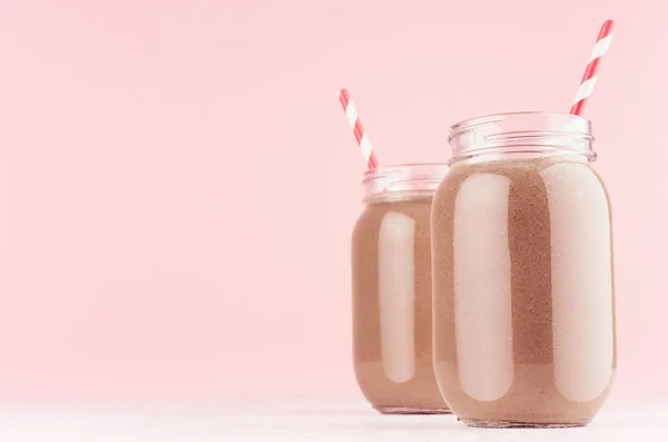 精致的淡牛奶巧克力甜点在罐子与红色稻草在现代优雅的粉红色背景 — 图库照片