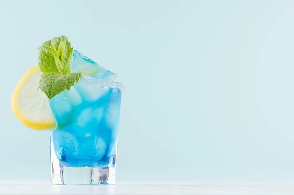 魅力热带水果蓝色鸡尾酒与库拉索 绿色薄荷 柠檬片在雾化的射砂玻璃在现代薄荷颜色内饰的白色木表 — 图库照片