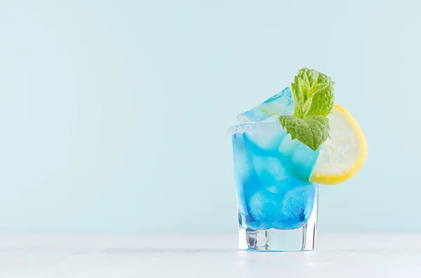 明亮的夏季新鲜蓝色水果鸡尾酒与蓝色库拉索酒 糖边缘 绿色薄荷 柠檬在白木板上的粉色薄荷内部 — 图库照片