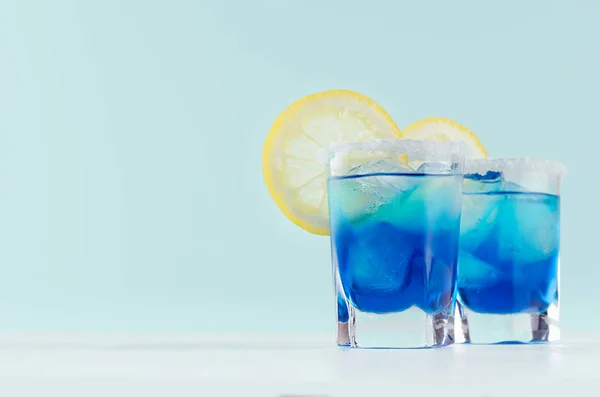 精致的蓝色鸡尾酒 以海滩风格庆祝 蓝色库拉索 糖边缘 薄荷色条内部的柠檬片在白色木桌上 — 图库照片