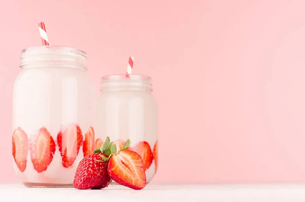 春天健康牛奶饮料与切成熟的草莓 红色条纹稻草在柔和的粉红色背景 白色木表 — 图库照片