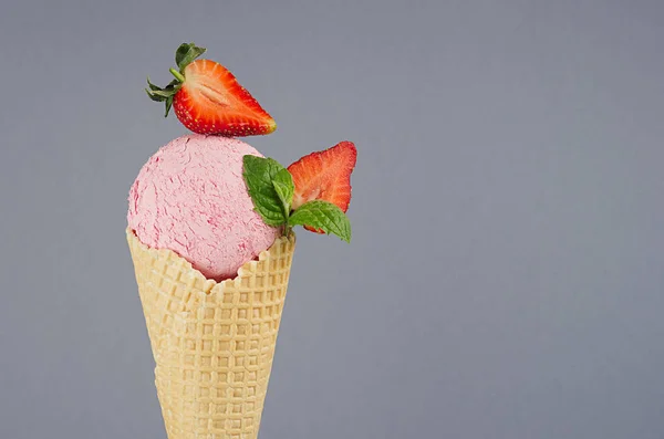 イチゴのスライスと鮮明なワッフルコーンのピンクのアイスクリーム 柔らかい光パステルグレーの背景にミントリーフ クローズアップ トップ — ストック写真
