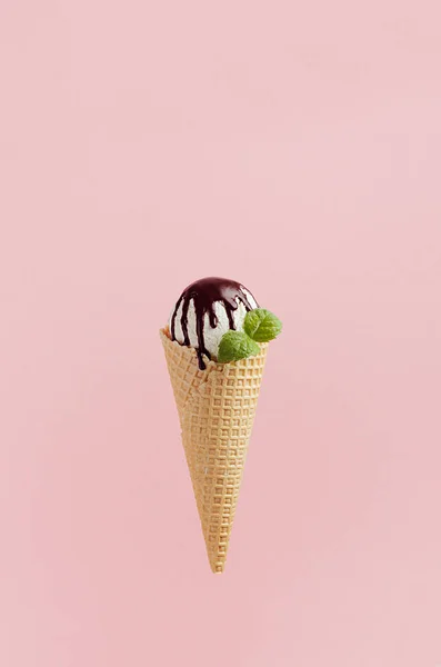 サクサクのワッフルコーンでおいしい白いアイスクリームスクープは チョコレートソースを飾った ピンクの背景にミントの葉 — ストック写真