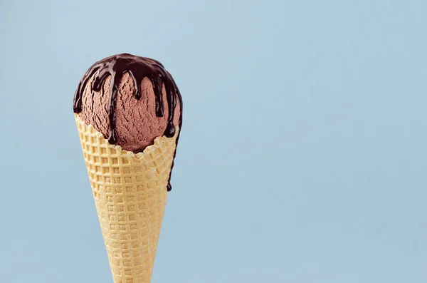 柔らかい光パステルブルーの背景にチョコレートソースとワッフルコーンのブラウンアイスクリーム クローズアップ トップ — ストック写真