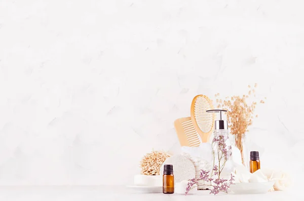 Homemade cosmetic products and natural wood accessories for hygiene and skin cleansing, spa with elegant lavender twig in soft light white interior on wooden table with copy space.