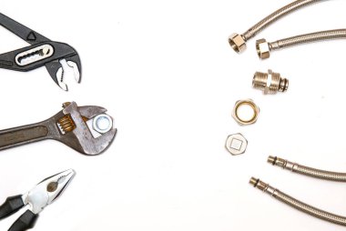 Maymun anahtarı, ayarlanabilir anahtar ve metal esnek borular. Beyaz arka planda tesisat aletleri. Tuvaletlerdeki, lavabolardaki ve küvetlerdeki boru ve muslukları tamir etme kavramı. Boşluğu kopyala.