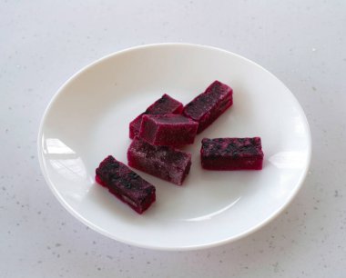 Beyaz bir çay tabağında doğal kızılcık ve agar marmeladı dilimleri. yakın plan