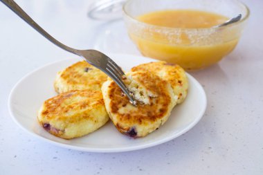 Beyaz bir tabakta beyaz bir çatalla krep, bir kase bal, hafif bir arka plan. Kahvaltı konsepti.