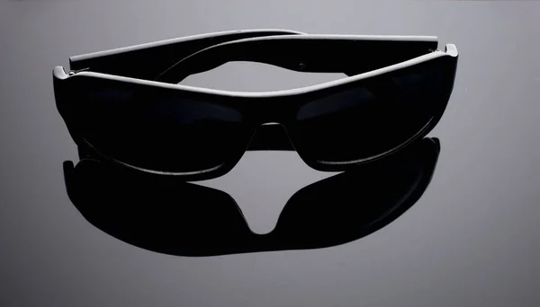 Detailní záběr černé sluneční brýle na šedém pozadí. — Stock fotografie