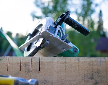 Tahtada bir alet çantası var. Elektrikli testere ve çekiç. Ahşap evler, çerçeve evler yapma fikri..