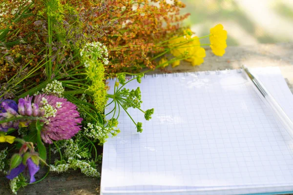 sunny summer day and wildflowers with a notebook and pen