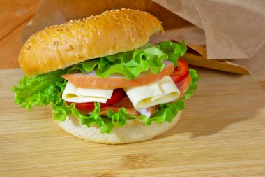 Tahta arka planda domates, peynir ve marullu göğüs eti sandviçi. abur cubur.