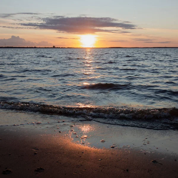 Sole al tramonto, riflesso del fiume paesaggio acquatico. Ci sono tracce di un cane sulla sabbia. nuvole nel cielo, — Foto Stock