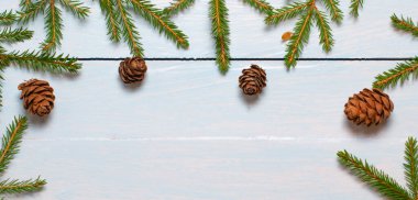 Yılbaşı konisi olan bir Noel ağacının dalları tahtadaki beyaz-mavi arka planda. Düz konum, üst görünüm, kopyalama alanı.