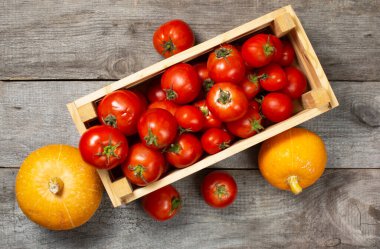 Ahşap masa arkasında domatesli ahşap kutu ve balkabağı, sade yaşam, hasat konsepti, kimyasalsız ürünler, sağlıklı yiyecekler..