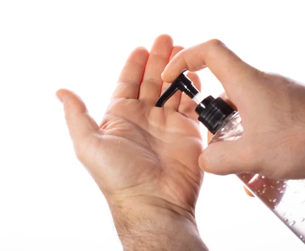 En man klämmer antiseptisk gel från en genomskinlig plastflaska på händerna på en vit bakgrund. konceptet att motverka viruset, rena händer. — Stockfoto