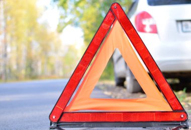 Beyaz bir araba ve ormanın arka planında dur işareti var. Yol yardımı kavramı, seyahat hadiseleri, araba tamiri. Boşluğu kopyala