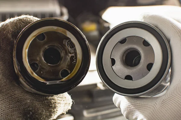 Araba için motor yağı değiştiren, eldivenli bir adam eski ve yeni bir yağ filtresi tutuyor. konsept araba bakım ve onarım. Boşluğu kopyala.