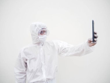 PPE süit üniformalı genç bir doktor ya da bilim adamı telefonunu selfie çekmek ve aile veya Freind ile görüntülü sohbetler yapmak için kullanıyordu. Coronavirus veya COVID-19 kavramı izole edilmiş beyaz arkaplan