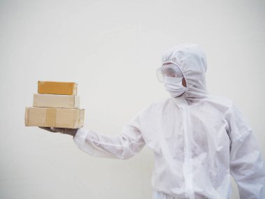 Plastik eldiven ve maske içinde karton kutular taşıyan PPE süit üniformalı genç bir adam. Coronavirus veya COVID-19 kavramı izole edilmiş beyaz arkaplan