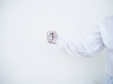 PPE üniformalı Asyalı doktor ya da bilim adamı beyaz bir arka planda mesaj ya da tasarım için yumruğunu sıktığını gösteriyor. Coronavirus veya COVID-19 kavramı