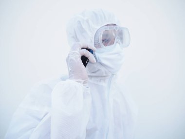 PPE süit üniformalı genç doktor ya da bilim adamı aile ya da arkadaşıyla telefonda konuşuyor. Coronavirus veya COVID-19 kavramı izole edilmiş beyaz arkaplan