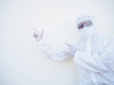 PPE süit üniformalı Asyalı erkek doktor ya da bilim adamı iki parmağını fotokopi çekerken ileri ve ileri doğru bakıyor. Coronavirus veya COVID-19 kavramı izole edilmiş beyaz arkaplan