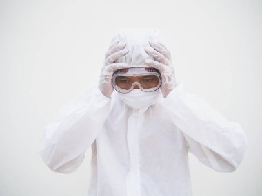 PPE süit üniformalı Asyalı erkek doktor ya da bilim adamı elini baş ağrısı ve kırışıklık hissi ile kafasına koyuyor. Coronavirus veya COVID-19 kavramı izole edilmiş beyaz arkaplan