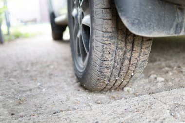 Araba tekerleği görüntüsü. Yolda duran arabanın arka tekerleği görünüyor. Yakın çekim.