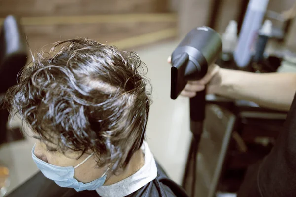 Hairdressing services during coronavirus. Hairdresser in face mask cuts hair of woman in face mask. Hairdressers cutting hair during COVID-19