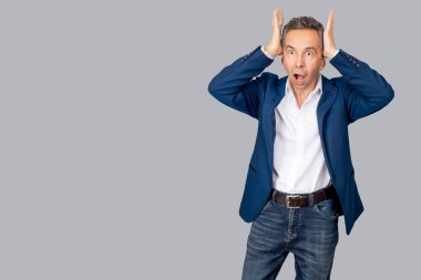 Çekici bir adam kafasını ellerinin arasına aldı. Adam panik jesti gösteriyor. İzole edilmiş gri arka plan. Boşluğu kopyala