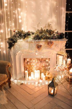 Noel iç tasarımında sıcak ve sıcak bir akşam, ışıklarla süslenmiş Xmas ağacı hediyeler, oyuncaklar, geyikler, mumlar, fenerler, kapalı alanda yanan şömine. tatil salonu sihirli yeni yıl