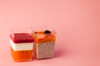 İki sulu tatlı, puding, chia tohumu, mango püresi, böğürtlen, çok katmanlı, panakota, pembe arka planda tutkulu hindistan cevizi sütü. metin için boşluk kopyala