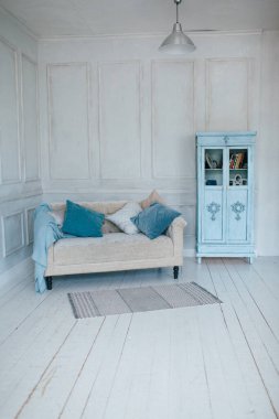 Kanepesi ve doğal renklerde yastıkları olan parlak oturma odası. Mavi ekose ve İskandinav tarzında gardırop.