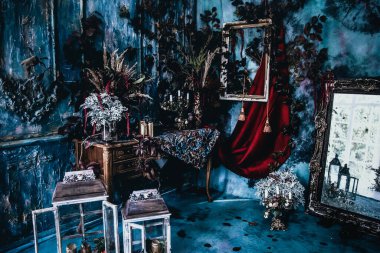 Kurumuş çiçekler, vazolar, avizeler, altın çerçeveli kumaşlar, lüks kraliyet tarzı ahşap bir masa, eski fenerlerle yanan mumlar.