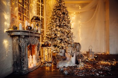 Noel iç tasarımında sıcak ve sıcak bir akşam, ışıklarla süslenmiş Xmas ağacı hediyeler, oyuncaklar, geyikler, mumlar, fenerler, kapalı alanda yanan çelenkler.