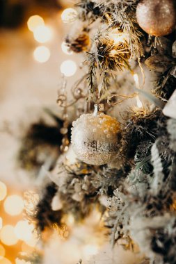 Noel ağacındaki klasik Noel ağacı oyuncağının yakın plan fotoğrafı. Altın rengi süslemeler, çelenk ışıkları. Mutlu yıllar ve Noel