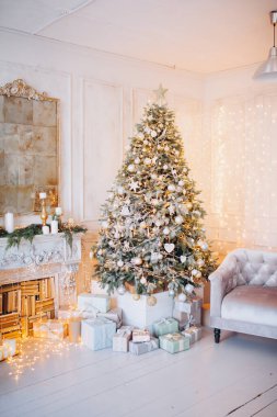 Noel ağacı ve dekoratif şömineyle süslenmiş, zarif, aydınlık renkte bir oda tasarımı.