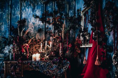 Kurumuş çiçekler, vazolar, avizeler, altın çerçeveli kumaşlar, lüks kraliyet tarzı ahşap bir masa, eski fenerlerle yanan mumlar.